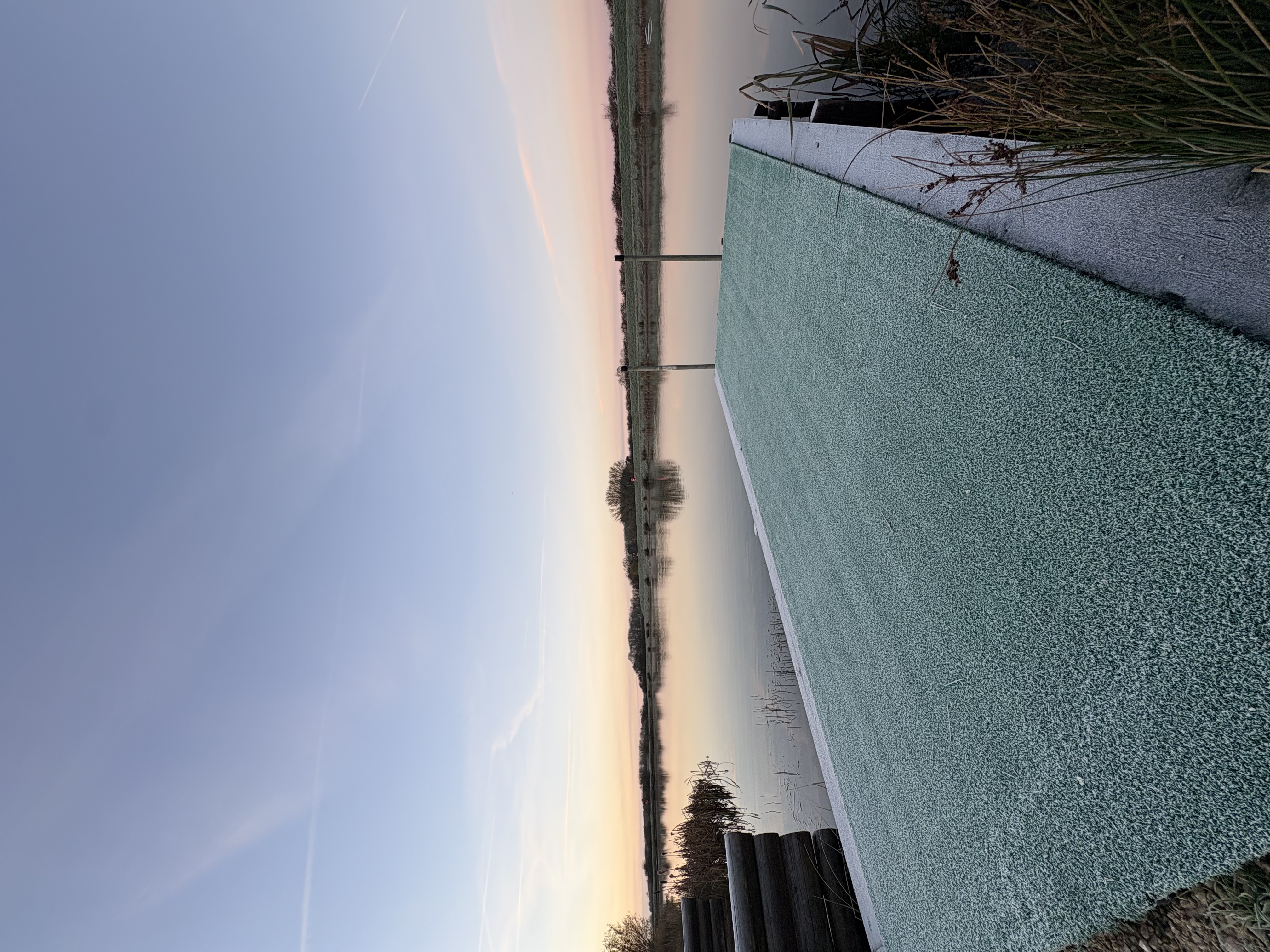 Frost on the reservoir jetty beneath a pale winter sky